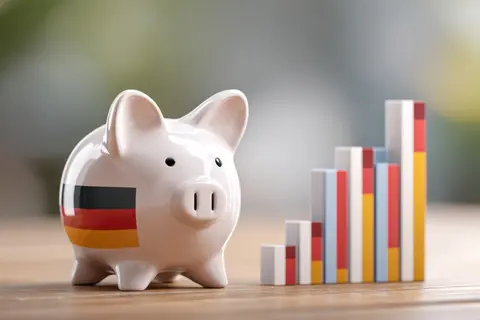 Economic Growth of Germany: A piggy bank adorned with German flag next to a rising bar graph, highlighting financial growth and the nation's economic 